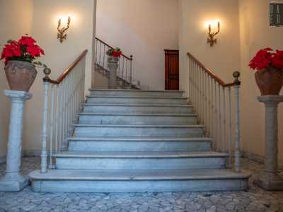 Accediamo all�atrio illuminato da due lampioncini dorati e occupato da un�elegante scala in marmo delimitata da colonnine che sorreggono due vasi